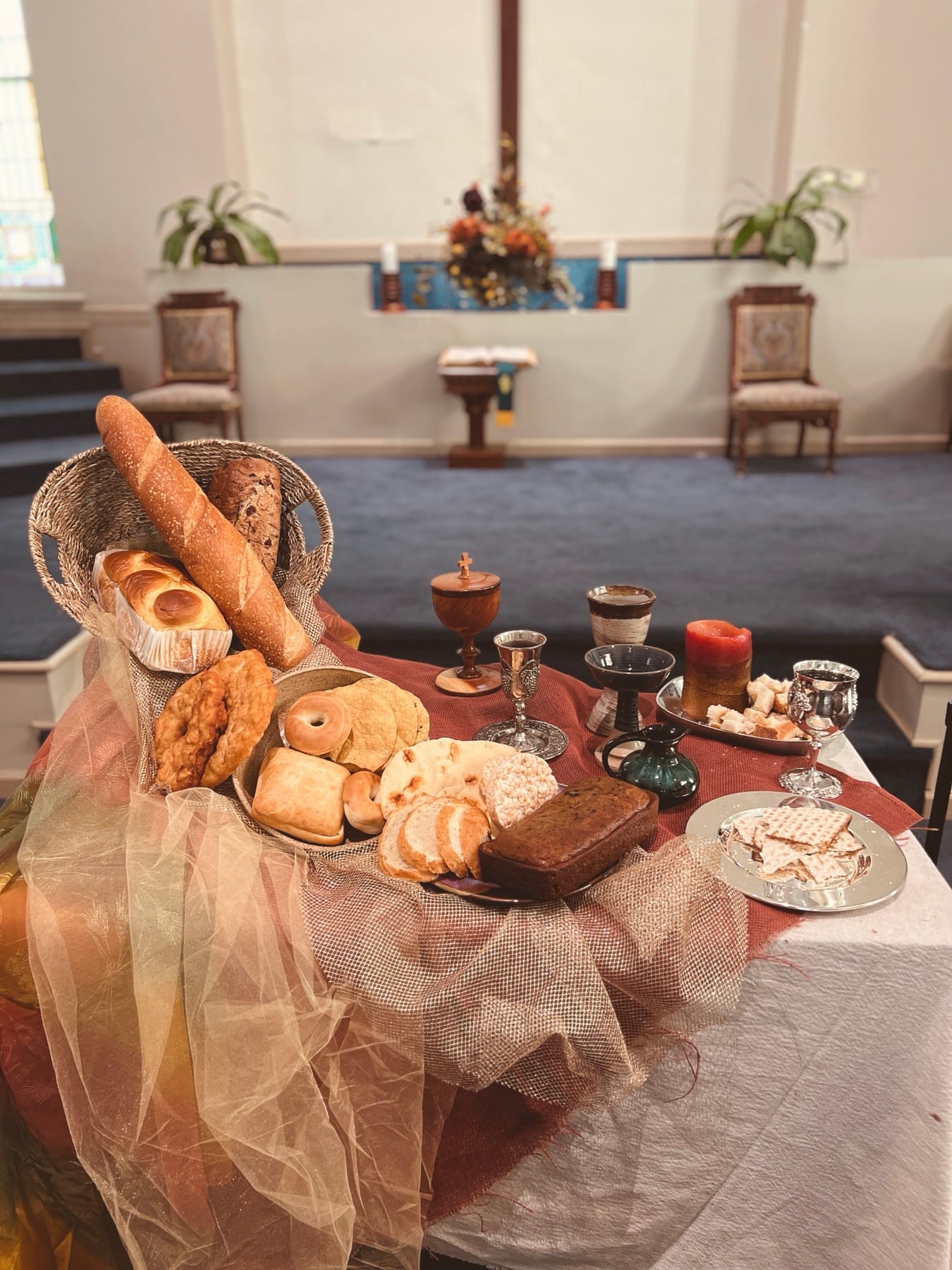 A communion table arranged with breads, cups, candles, and serving vessels